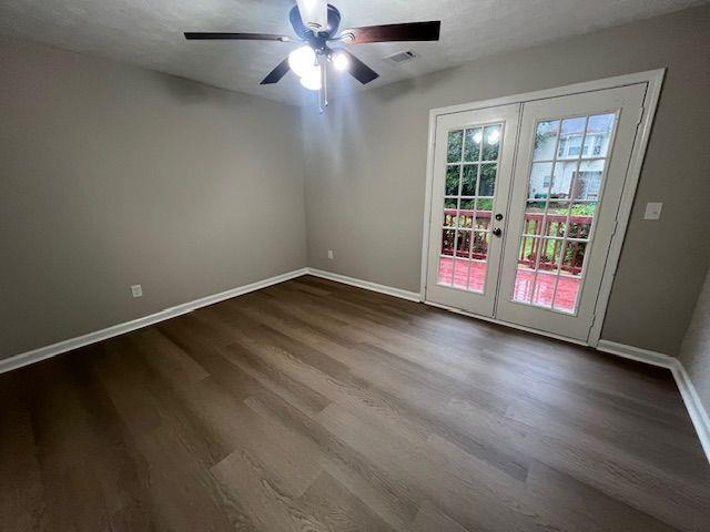 spare room with dark wood-style flooring, ceiling fan, visible vents, baseboards, and french doors