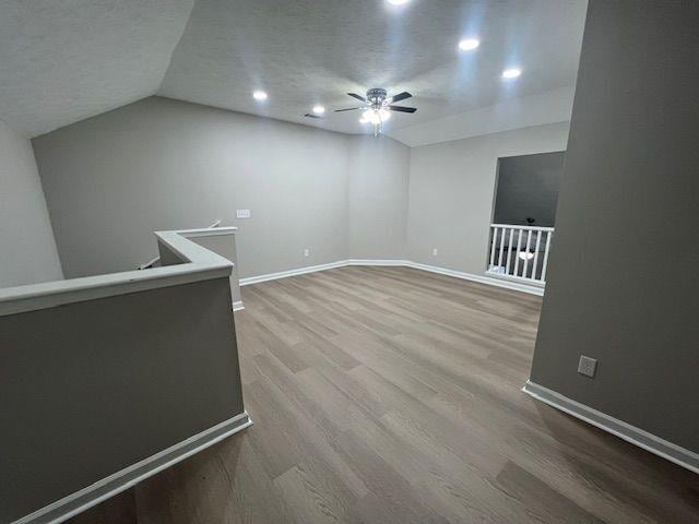 additional living space with recessed lighting, wood finished floors, a ceiling fan, baseboards, and lofted ceiling