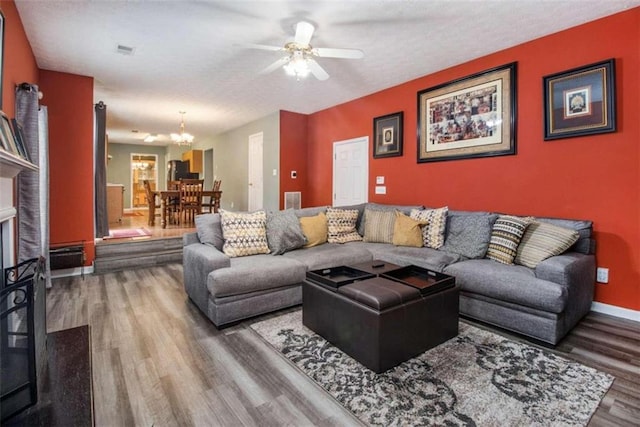 living room featuring ceiling fan with notable chandelier and hardwood / wood-style floors