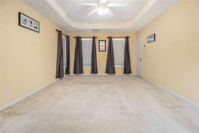 unfurnished room with light carpet, a raised ceiling, and ceiling fan