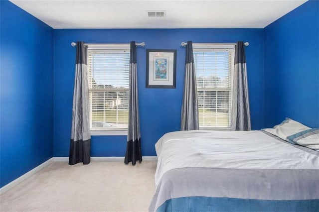 bedroom with light carpet and multiple windows