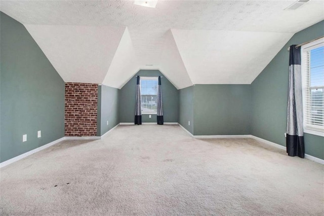 additional living space with light colored carpet, a textured ceiling, lofted ceiling, and a healthy amount of sunlight