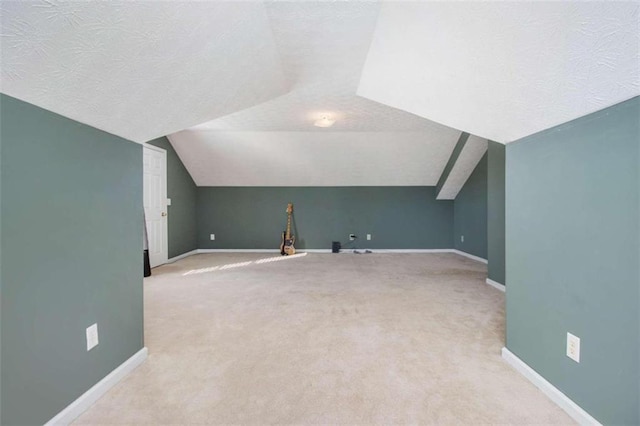 additional living space featuring lofted ceiling, a textured ceiling, and light colored carpet