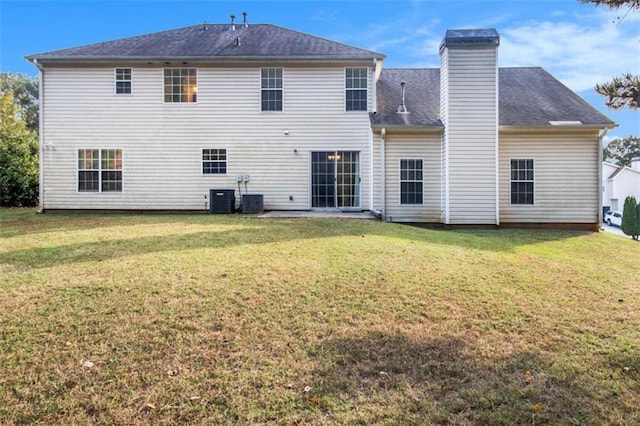 rear view of house with cooling unit and a yard