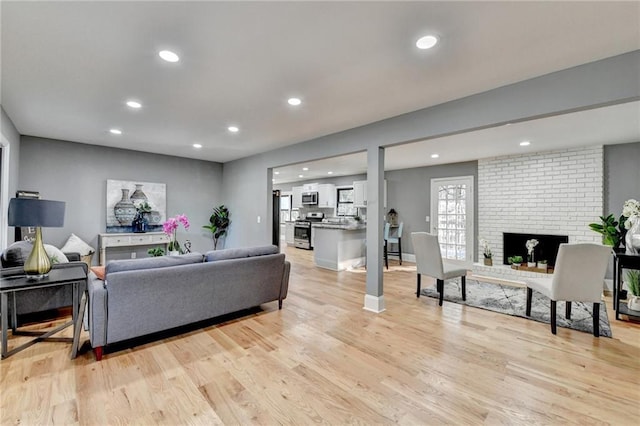 living room featuring light hardwood / wood-style floors and a brick fireplace