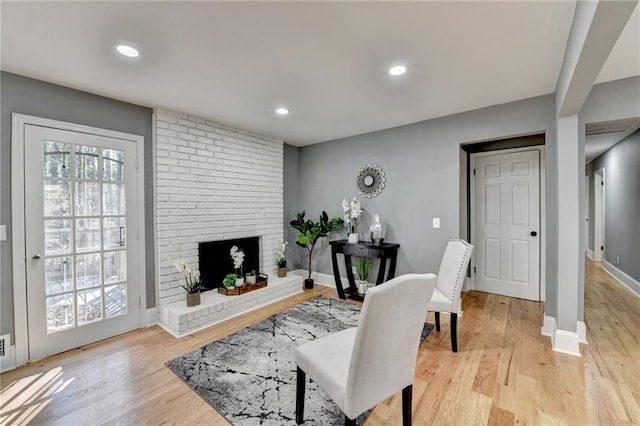 living room featuring light hardwood / wood-style floors and a brick fireplace