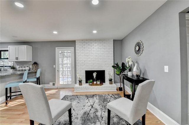 living room featuring a healthy amount of sunlight, light wood-type flooring, and a fireplace