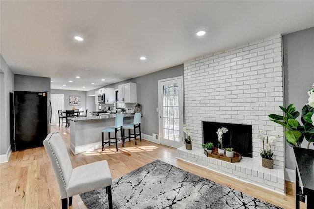 living room with light hardwood / wood-style floors and a brick fireplace