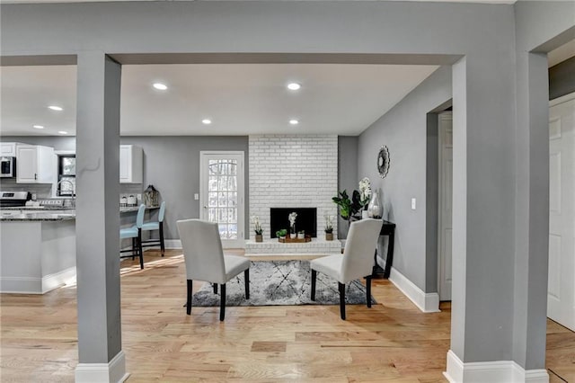 office area featuring light wood-type flooring and a brick fireplace