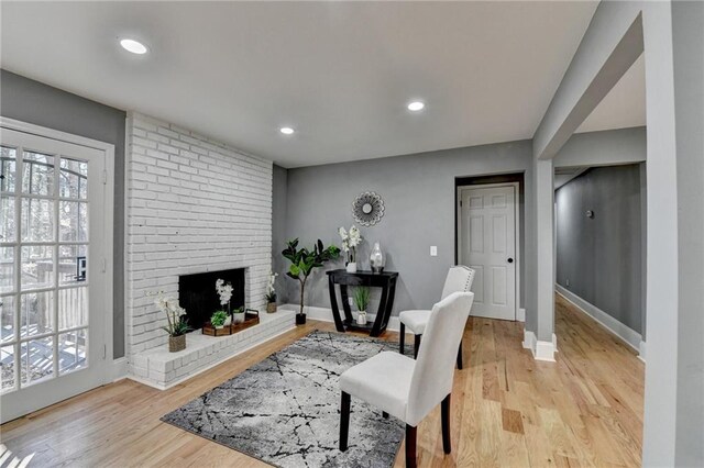 living room featuring light wood-type flooring and a brick fireplace