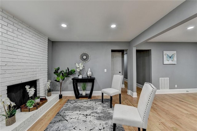 sitting room with hardwood / wood-style floors and a brick fireplace