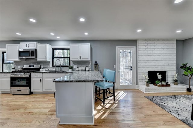 kitchen featuring white cabinetry, a fireplace, and appliances with stainless steel finishes