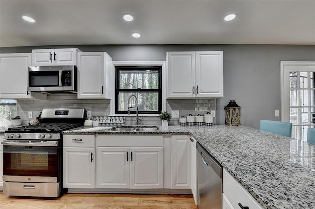 kitchen featuring light stone counters, white cabinetry, sink, and appliances with stainless steel finishes