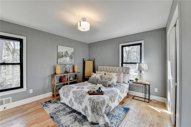 bedroom with a closet, light hardwood / wood-style flooring, and multiple windows