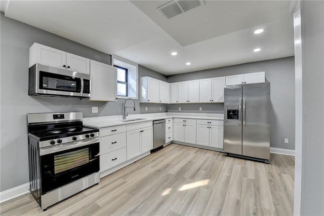 kitchen with white cabinets, light wood-type flooring, sink, and appliances with stainless steel finishes