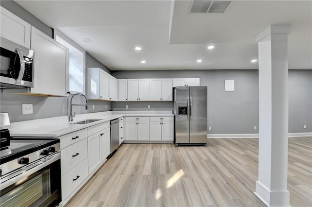 kitchen featuring white cabinetry, sink, appliances with stainless steel finishes, and light hardwood / wood-style flooring