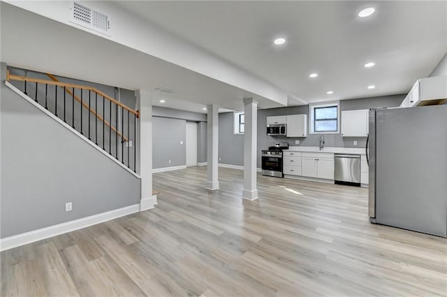 kitchen with white cabinets, appliances with stainless steel finishes, and light hardwood / wood-style flooring