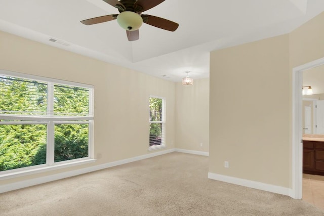 carpeted spare room with ceiling fan with notable chandelier and plenty of natural light