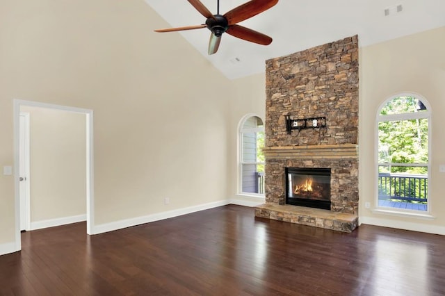 unfurnished living room with a stone fireplace, high vaulted ceiling, dark wood-type flooring, and ceiling fan