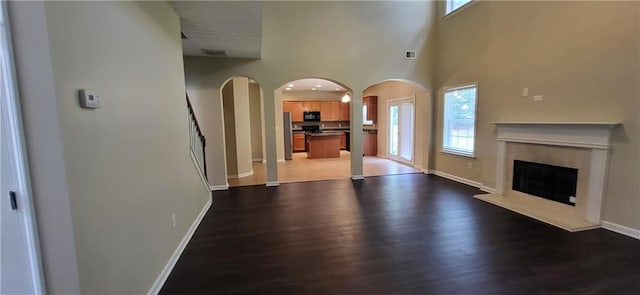 571 Cold Water Ln, Mcdonough, GA 30252 - unfurnished living room featuring arched walkways, wood finished floors, a fireplace, and a high ceiling