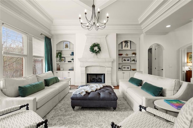 living room featuring crown molding, built in shelves, arched walkways, a notable chandelier, and a fireplace