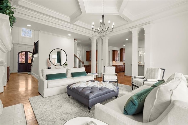 living room with light wood-style flooring, a notable chandelier, stairway, and ornate columns