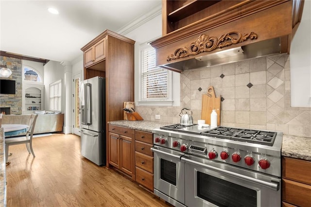 kitchen with ornamental molding, brown cabinets, custom exhaust hood, and premium appliances