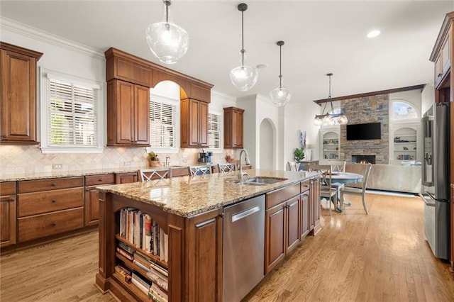 kitchen with open floor plan, ornamental molding, a sink, and appliances with stainless steel finishes