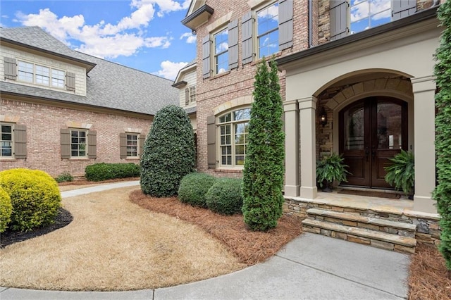 view of exterior entry featuring brick siding and french doors