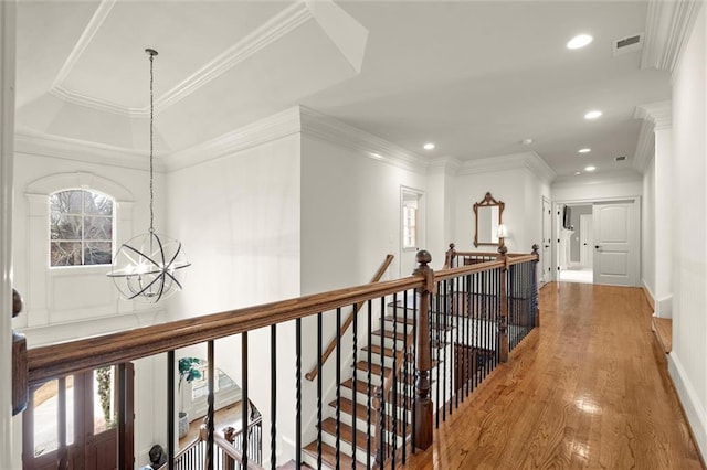corridor with an upstairs landing, crown molding, visible vents, a notable chandelier, and wood finished floors