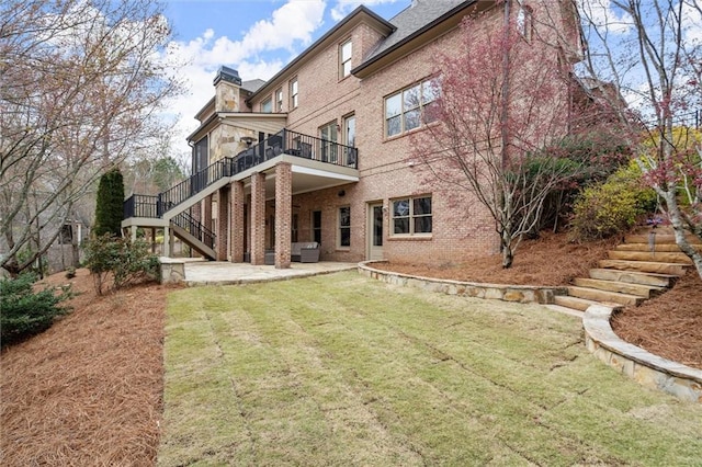 back of house with stairs, a chimney, a patio, and brick siding