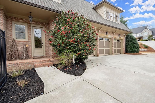 property entrance featuring brick siding, driveway, roof with shingles, and an attached garage