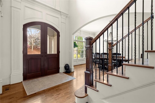 foyer entrance with stairs, a high ceiling, wood finished floors, and arched walkways