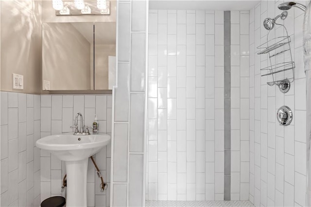 bathroom with a tile shower, tile walls, and a sink