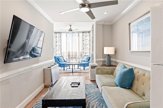 living area with baseboards, ornamental molding, and wood finished floors