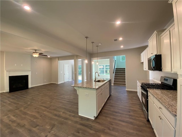 kitchen with stainless steel gas range, a sink, a ceiling fan, baseboards, and a fireplace