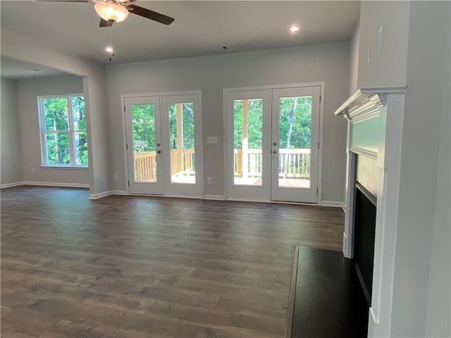 unfurnished living room with a fireplace, ceiling fan, french doors, baseboards, and dark wood finished floors