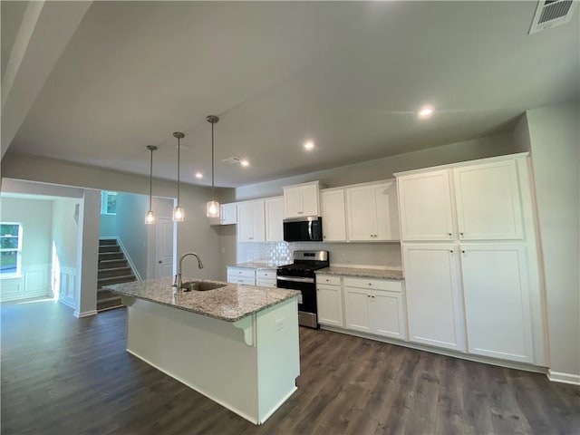 kitchen featuring appliances with stainless steel finishes, a sink, white cabinetry, a center island with sink, and dark wood-style floors