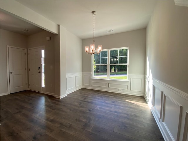 unfurnished dining area with a chandelier, dark wood-type flooring, wainscoting, and a decorative wall