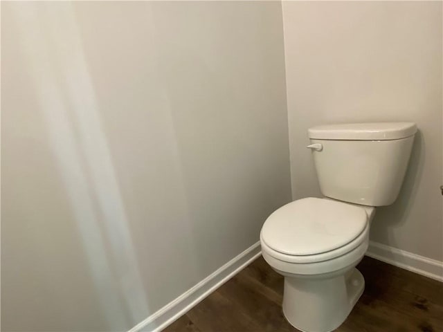 bathroom with wood finished floors, baseboards, and toilet