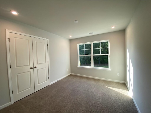 unfurnished bedroom featuring baseboards, carpet floors, recessed lighting, and a closet
