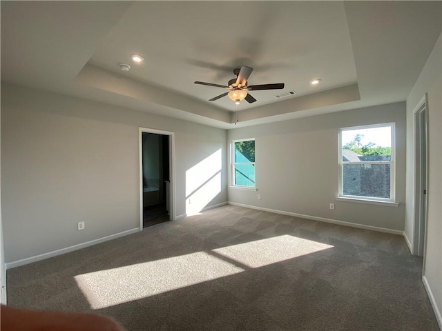 unfurnished bedroom with a raised ceiling, baseboards, carpet floors, recessed lighting, and ensuite bath