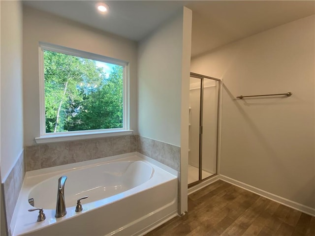 full bath with a bath, a stall shower, and wood finished floors