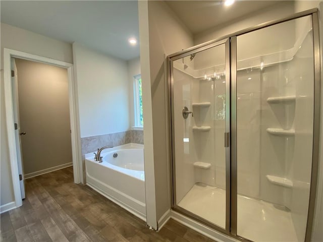 full bathroom featuring a bath, a shower stall, wood finished floors, baseboards, and recessed lighting