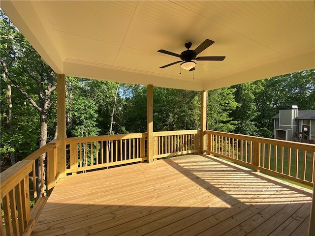 wooden deck with ceiling fan and view of wooded area