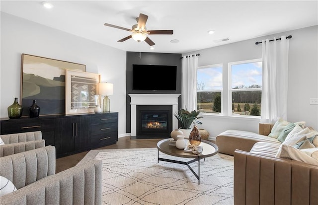 living area with visible vents, a ceiling fan, a glass covered fireplace, wood finished floors, and recessed lighting