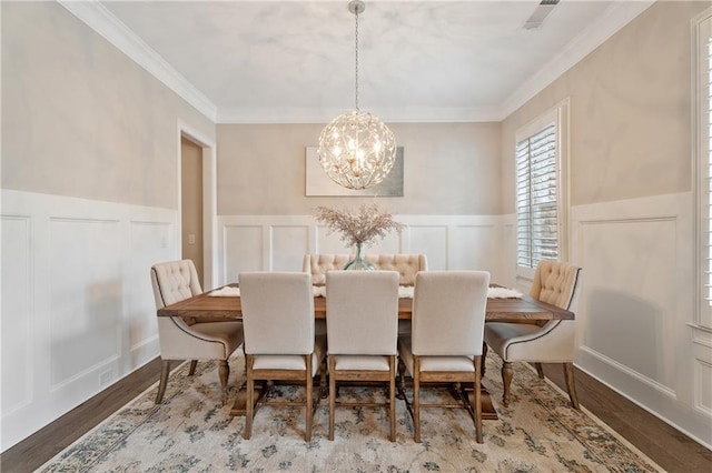 dining space featuring hardwood / wood-style floors, ornamental molding, and a chandelier