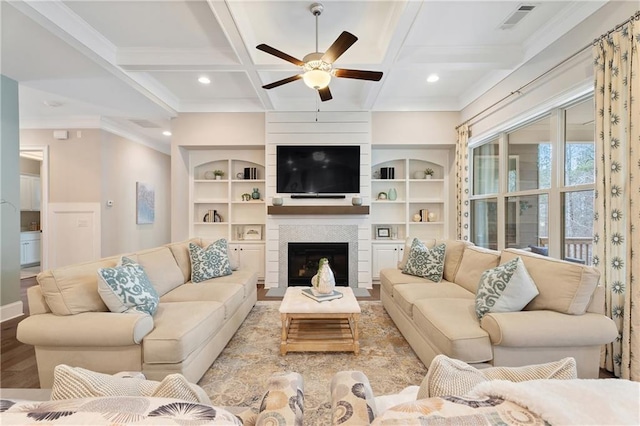 living room featuring built in shelves, ceiling fan, coffered ceiling, and beamed ceiling