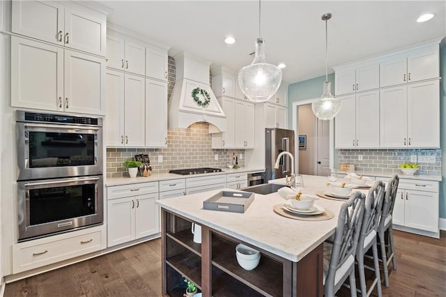 kitchen with custom exhaust hood, a center island with sink, and white cabinets