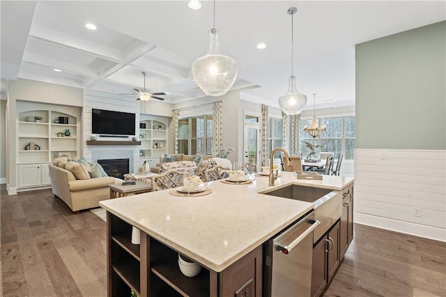 kitchen with sink, dishwasher, beam ceiling, coffered ceiling, and a center island with sink